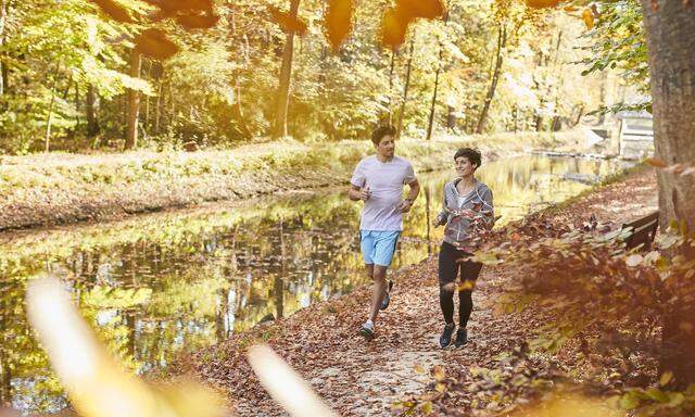 Couple jogging on autumnally forest track model released Symbolfoto PUBLICATIONxINxGERxSUIxAUTxHUNx