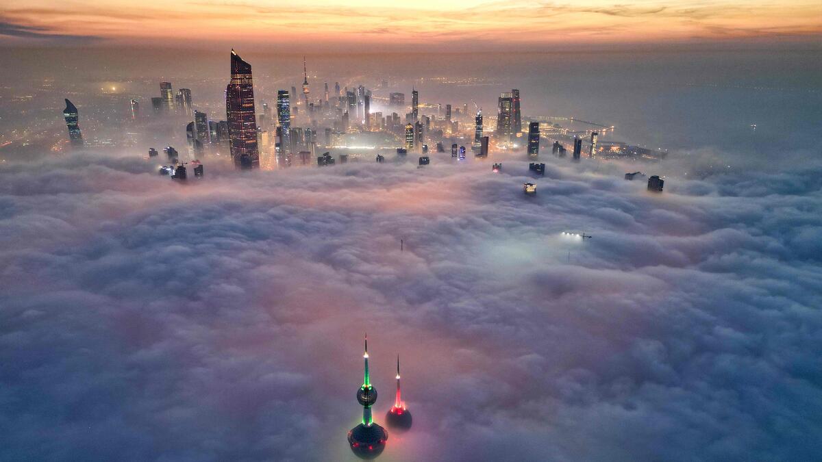TOPSHOT - In this aerial view, the landmark Kuwait Towers and other skyscrapers pierce through the cloud cover over Kuwait City on December 10, 2023. (Photo by Yasser Al-Zayyat / AFP)