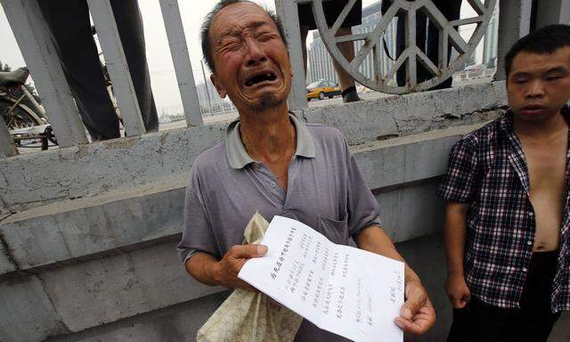 File picture shows a man crying as he shows his petitioning paper to Reuters journalists near the State Bureau for Petitions and Visits in Beijing