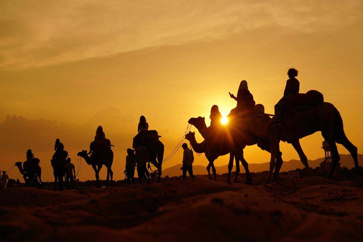 10. September. Touristen genießen in der Nähe der indischen Kleinstadt Pushkar eine Kamelsafari durch Wüste.
