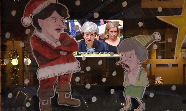 People in a bar watch Britain´s Prime Minister Theresa May during a debate in the house of Commons on television as a window is illustrated with DUP leader Arlene Foster as Santa Claus and Theresa May as a Christmas Elf in Lisburn
