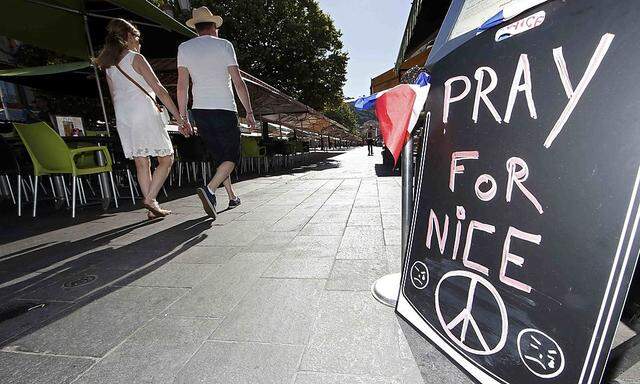  A couple walk through the empty flower market in the old city and near a sign which reads, 'Pray for Nice' days after a truck attack on the Promenade des Anglais on Bastille Day killed scores and injured as many in Nice