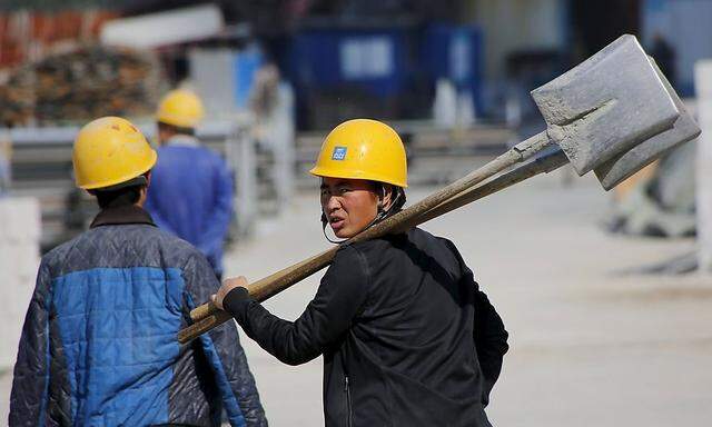 A worker walks past a road construction site in Beijing