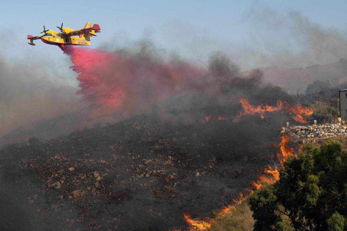 27. August. Ein Canadair-Flugzeug wirft Flammschutzmittel auf brennende Vegetation im sizilianischen Trapani.