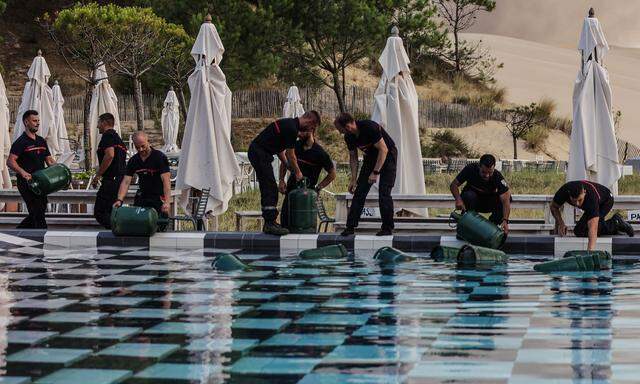 In einem Hotel in Pyla sur Mer legen Feuerwehrmänner Gaskartuschen zur Sicherheit ins Poolwasser.