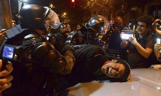A demonstrator is detained by riot police during a protest against Rio de Janeiro governor Sergio Cabral, near his residence in Rio de Janeiro