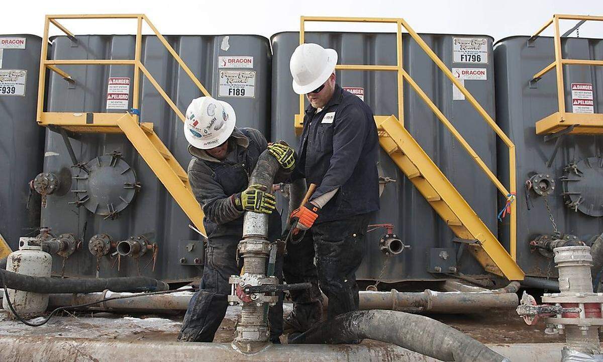 Mody Torres and Josh Anderson of Select Energy Services connect hoses between a pipeline and water tanks at a Hess fracking site near Williston