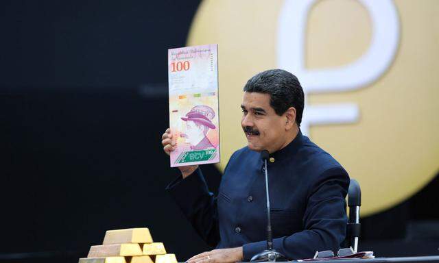 Venezuela's President Nicolas Maduro holds a specimen of the new one hundred-bolivar banknote during a meeting with ministers responsible for the economic sector at Miraflores Palace in Caracas