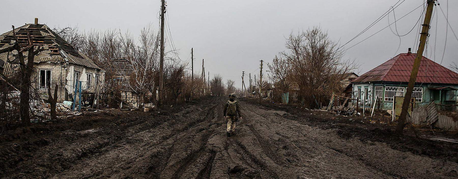 Ukrainian serviceman walks along a street in a village near the frontline town of Kreminna