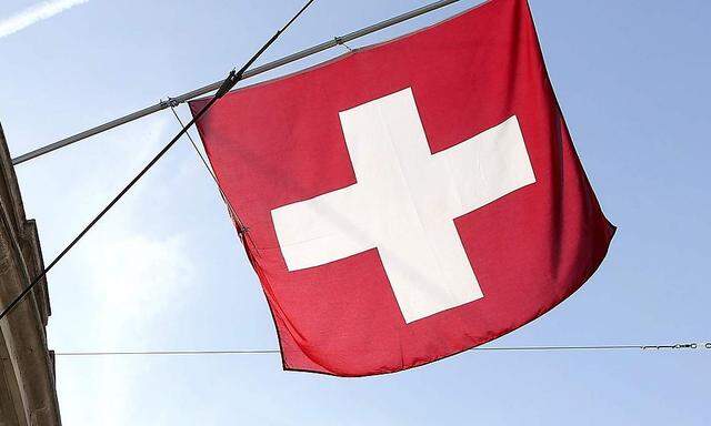 File photo of a Swiss national flag and a flag of the city of Basel flying over the entrance of a branch office of Swiss bank UBS in Basel