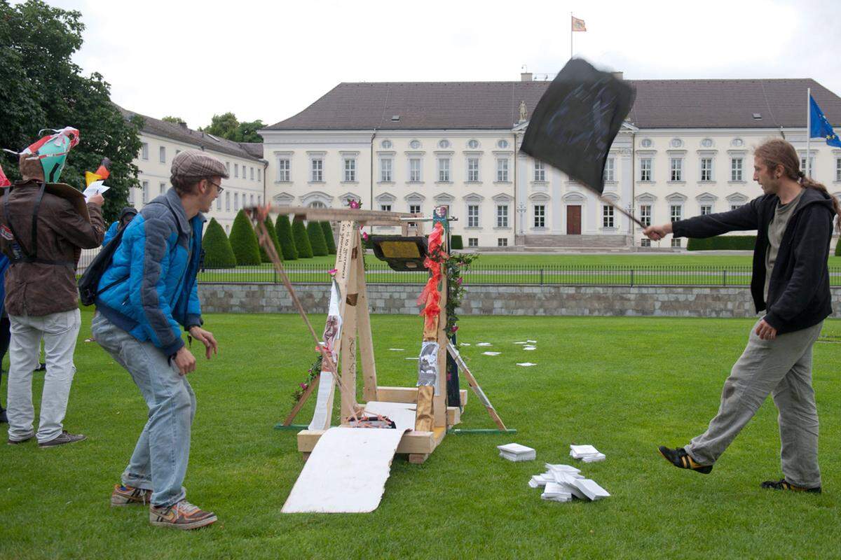 Occupy-Aktivisten beschießen das Schloss Bellevue in Berlin symbolisch mit einem Katapult. Als Munition dienen Ausgaben des Grundgesetzes. Damit soll gegen den Fiskalpakt demonsriert werden.