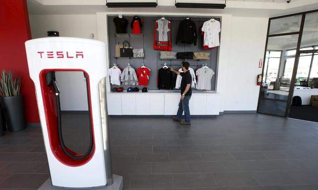 An employee adjusts a display at an showroom at a new Tesla dealership in Salt Lake City