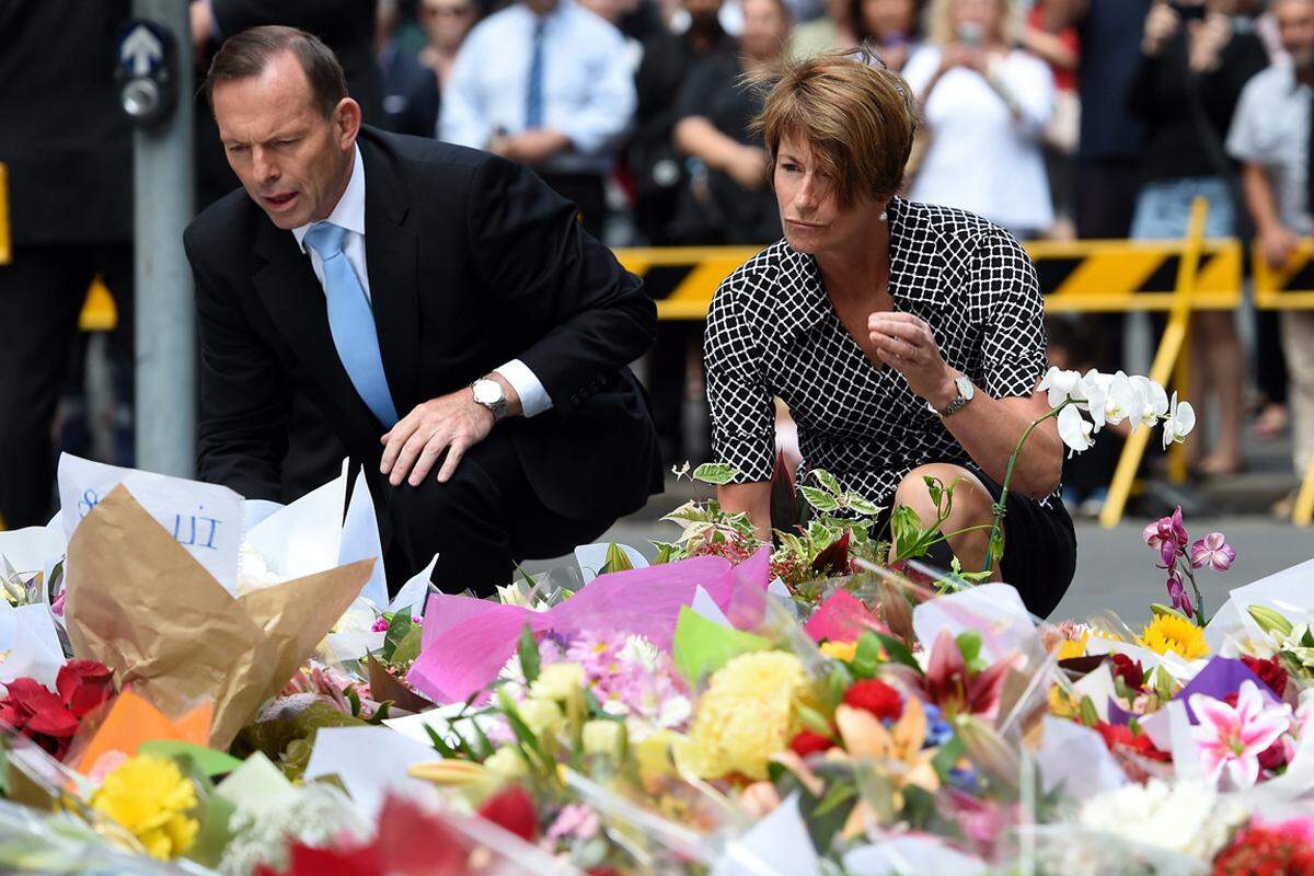 Vor dem "Lindt Chocolat Café" im Zentrum legen hunderte Menschen Blumen in Gedenken an die zwei Verstorbenen nieder - auch Australiens Ministerpräsident Tony Abbott und seine Frau Margie. Abbott bezeichnete den getöteten Geiselnehmer als "schwer gestörte Person" und stellte die Frage, warum er trotz schwerwiegender Anklagen auf freiem Fuß war.