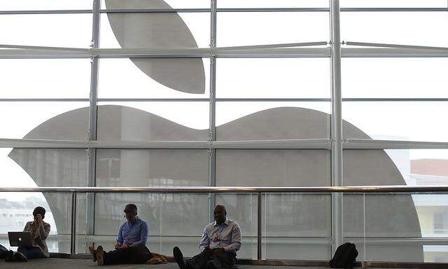Attendees sit in front of an Apple logo at the WWDC 2013 in San Francisco
