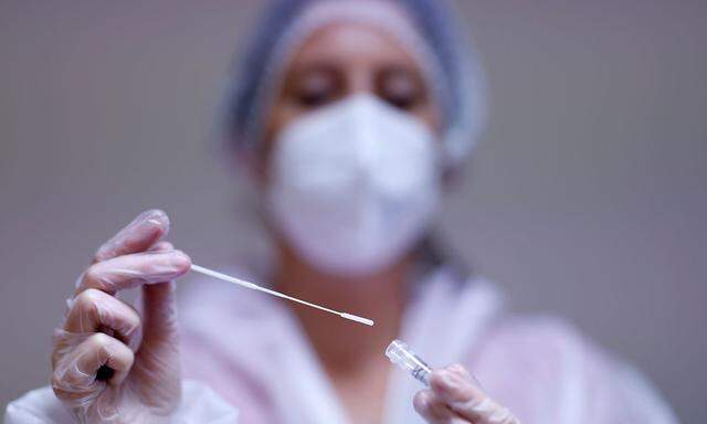 A medical worker holds a test tube after administering a nasal swab to a patient at a coronavirus disease (COVID-19) testing centre in Les Sorinieres