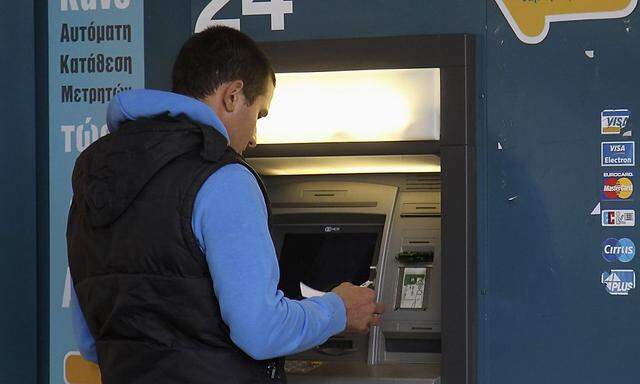 Man uses ATM outside Cypriot bank at the island's capital Nicosia