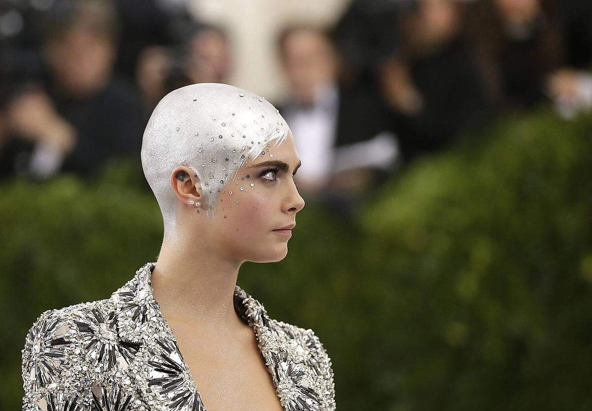 Mit einem futuristischen Lackanstrich am Kopf erschien das britische Model Cara Delevingne bei der Met Gala im Mai 2017 - der extravagante Look wurde erst überhaupt möglich, weil Delevingne, die auch als Schauspielerin arbeitet, für ihre Rolle im Film "Life in A Year" Haare lassen musste - alle nämlich. Seit dem Beginn der Dreharbeiten trägt sie eine Glatze. In dem Film spielt Delevingne ein Mädchen, das an Krebs erkrankt.