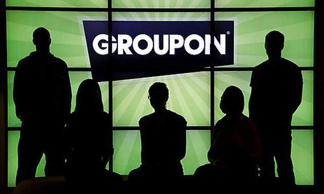 FILE - In this Sept. 22, 2011 file photo, employees at Groupon pose in silhouette with the company lo