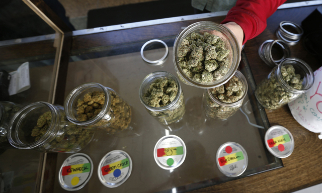 A volunteer displays jars of dried cannabis buds at the La Brea Collective medical marijuana dispensary in Los Angeles