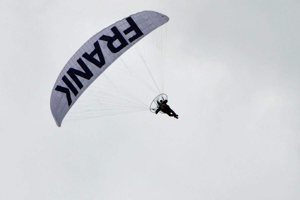 Gegen 18 Uhr erfüllt ein Donnern den Himmel über Eisenstadt. Drei motorisierte Paragleiter kreisen über dem Hauptplatz. Auf einem der Schirme prangt das Logo des Team Stronach, auf den anderen beiden ist je ein Wort zu lesen: "Jetzt", "Frank".