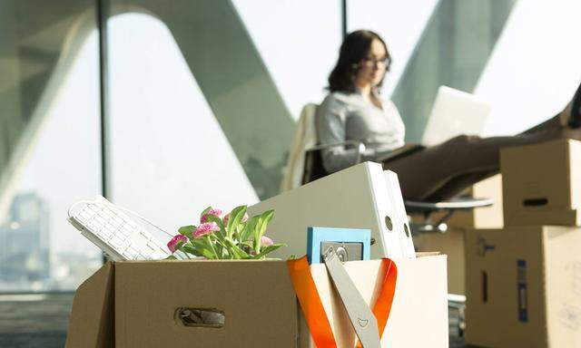 Cardboard box on office floor with businesswoman in background model released property released PUBL