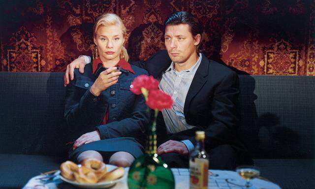 Mann und Frau schweigen sich an, das Gefühl liegt im Dekor (Blumen, Mehlspeise, Schnaps): ein typisch lakonisches Kaurismäki-Bild – aus dem Film „Lichter der Vorstadt“ („Laitakaupungin valot“, 2006).