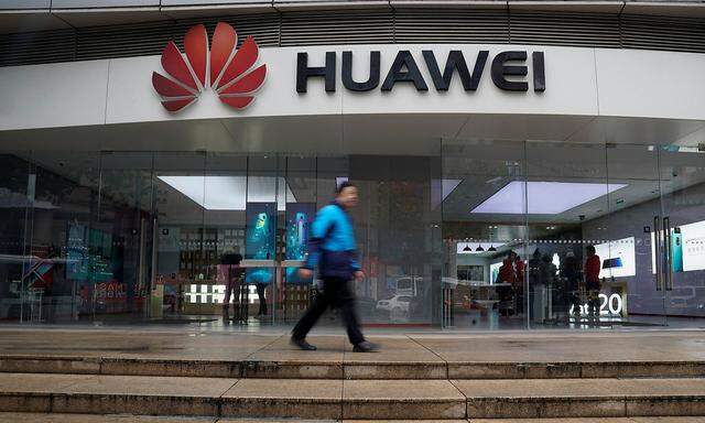 A man walks by a Huawei logo at a shopping mall in Shanghai