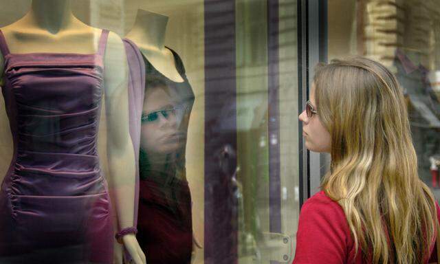 Frau betrachtet Kleidungsstuecke im Schaufenster