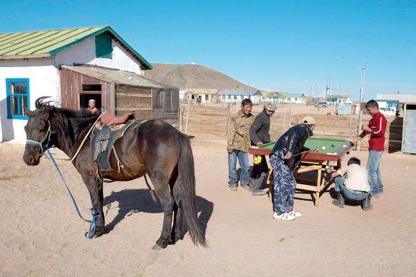 Mongolische Burschen machen einmal mit Open-Air-Billard Pause vom Pferd.