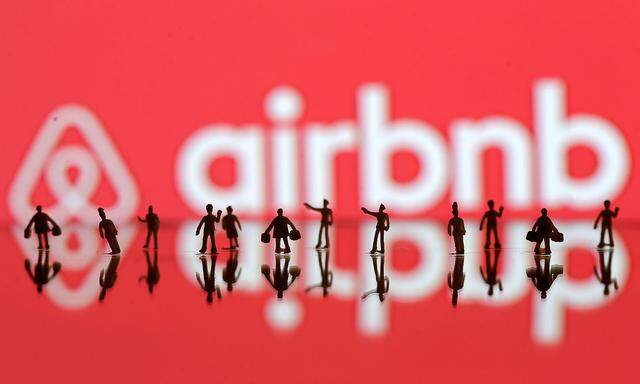 A 3D printed people models is seen in front of a displayed Airbnb logo in this illustration taken