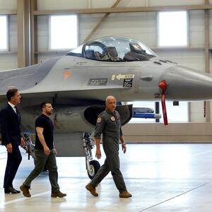 Wolodymyr Selenskij (Mitte) hinter dem holländischen Luftwaffenchef, General André Steur, und vor Premier Mark Rutte in Eindhoven, dahinter eine F-16. 