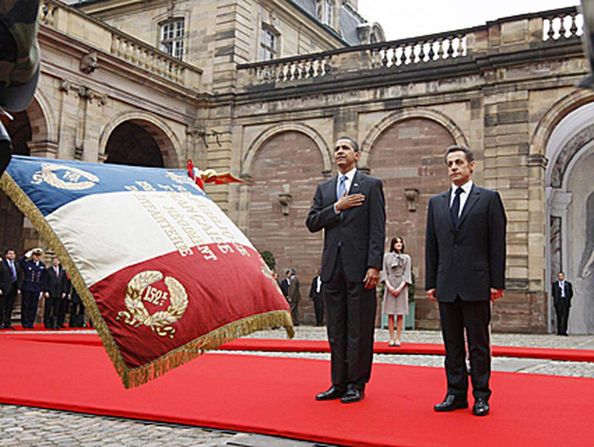 Obama kam im dunklen Anzug mit hellblauem Schlips, sie in einem pinkfarbenen Kleid mit schwarzem Überhang. Bei milden 13 Grad verzichtete der 47 Jahre alte Obama bei seinem ersten Besuch als Präsident auf dem europäischen Kontinent auf einen Mantel.
