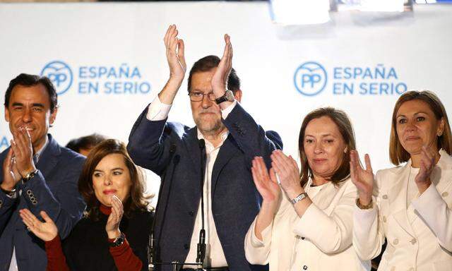 Trotz Wahlschlappe jubelt die Führungsriege der spanischen Volkspartei am Wahlabend über Position eins. Soraya Sáenz de Santamaría (l.), die Stellvertreterin und mögliche Nachfolgerin, und Ehefrau Elvira Fernandez (r., in Weiß) flankieren Premier Mariano Rajoy.