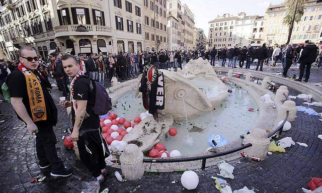 Feyenoord fans stand next to the fountain called 'Barcaccia' during clashes with police prior to the start of the Europa League soccer match between Roma and Feyenoord, at the Spanish Steps in Rome