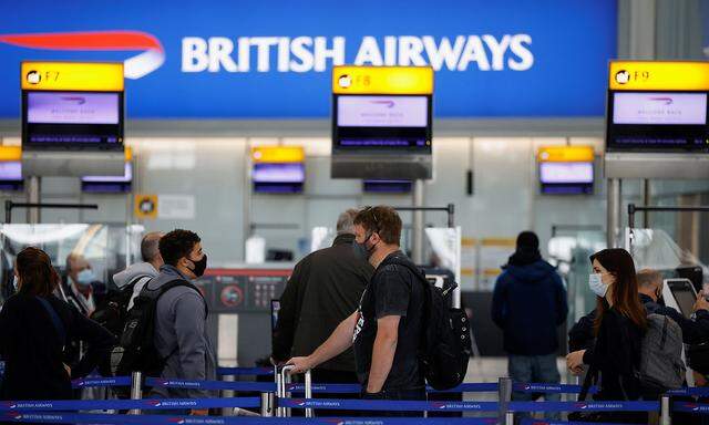 Passengers stand in a queue to the British Airways check-in desks at Heathrow Airport