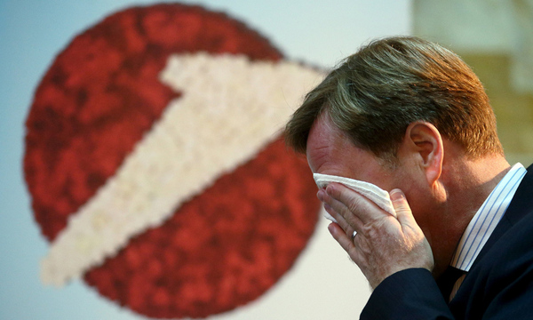 UniCredit unit Bank Austria Chief Executive  wipes his face as he passes a company logo before a news conference in Vienna