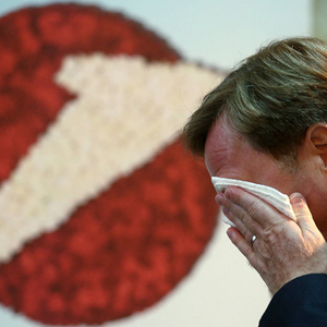 UniCredit unit Bank Austria Chief Executive  wipes his face as he passes a company logo before a news conference in Vienna