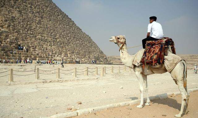 A policeman rides a camel while guarding the site at the pyramids plateau