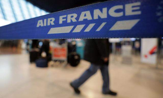 A passenger walks past an Air France sign at Nice Cote d'Azur airport as most of the flights are cancelled due to a storm in Nice