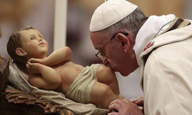 Pope Francis kisses the baby Jesus statue as he leads the Christmas night mass in the Saint Peter's Basilica at the Vatican