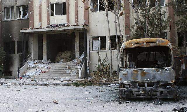 A burnt bus is seen in front of a damaged building in the Damascus suburb of Douma