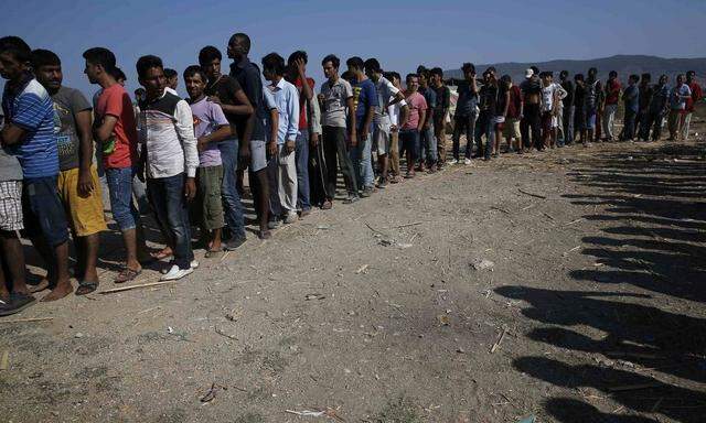 Migrants line up to receive sandwiches offered by volunteers of the organisation 'Solidarity Kos' outside Captain Elias, a derelict hotel where migrants find shelter on the Greek island of Kos