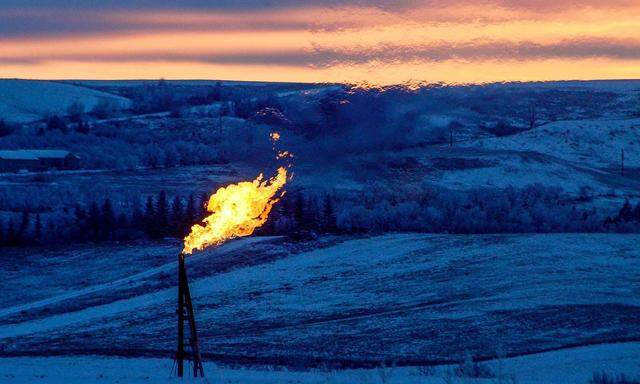 FILE PHOTO: A natural gas flare on an oil well pad burns as the sun sets outside Watford City, North Dakota