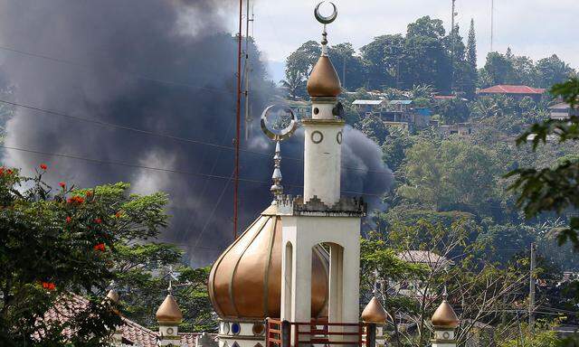 Rauch steigt hinter einer Moschee auf.