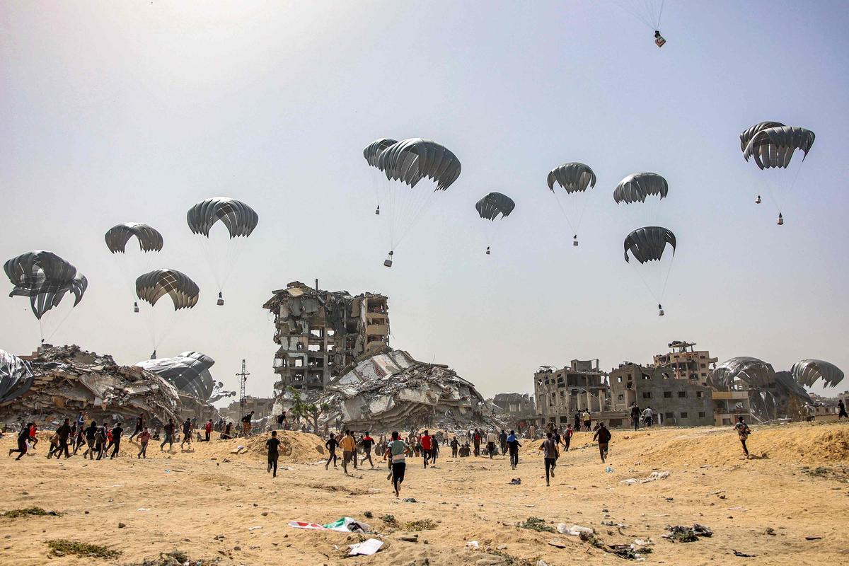23. April. Inmitten des anhaltenden Konflikts zwischen Israel und der militanten Hamas im Gazastreifen eilen Menschen zur Landung humanitärer Hilfspakete, die am 23. April 2024 über dem nördlichen Gazastreifen abgeworfen werden.
