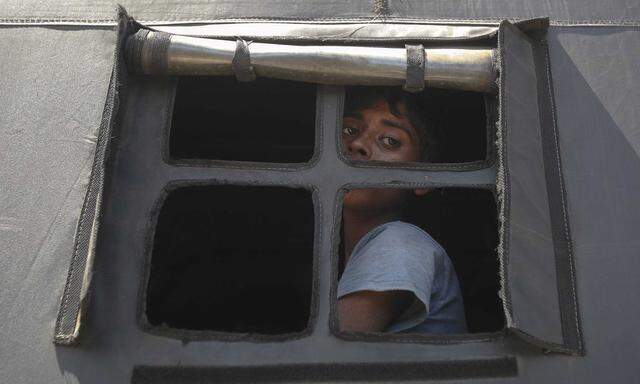 A Rohingya migrant who arrived today by boat looks out the window of a police truck before departing with others to a temporary shelter, in Idi Rayeuk