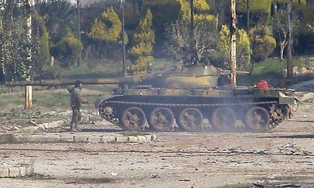A Syrian soldier stands near a Syrian tank in Bab Amro near the city of Homs