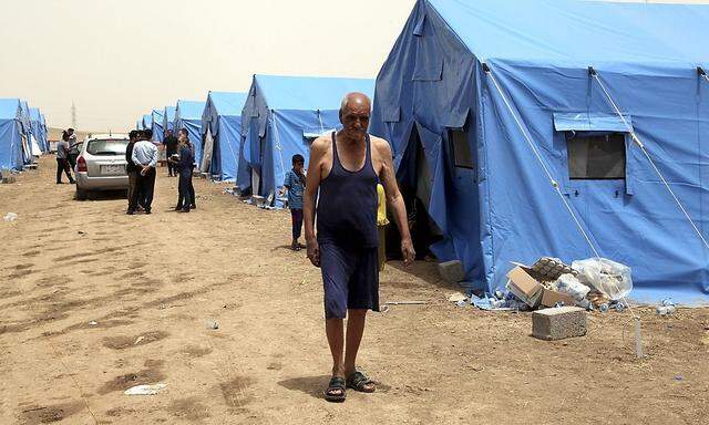 A man, who fled from the violence in Mosul, walks inside a camp on the outskirts of Arbil