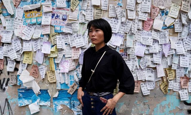 Eine Journalistin posiert vor einer Zettelwand in Hongkong.
