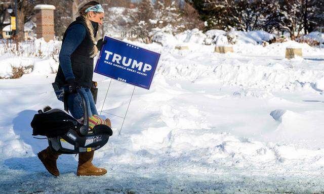 Eine Trump-Unterstützerin trägt nach dessen Wahlkampftermin am Sonntag in Indianola, Iowa ein Werbeschild für ihren Vorgarten nachhause - und ihr Baby.